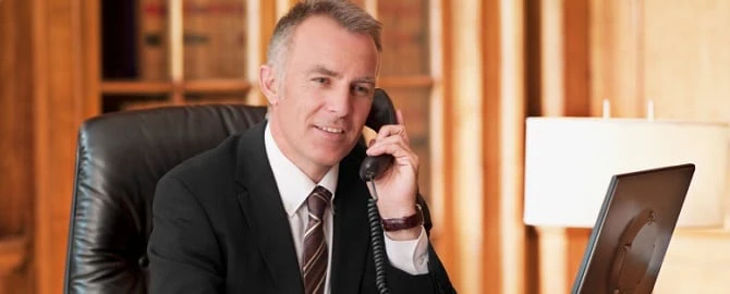 Businessman in a suit talking on the phone in an office setting.